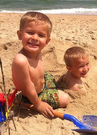 Two young boys playing in the beach sand
